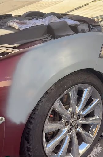 Red vehicle front fender in primer